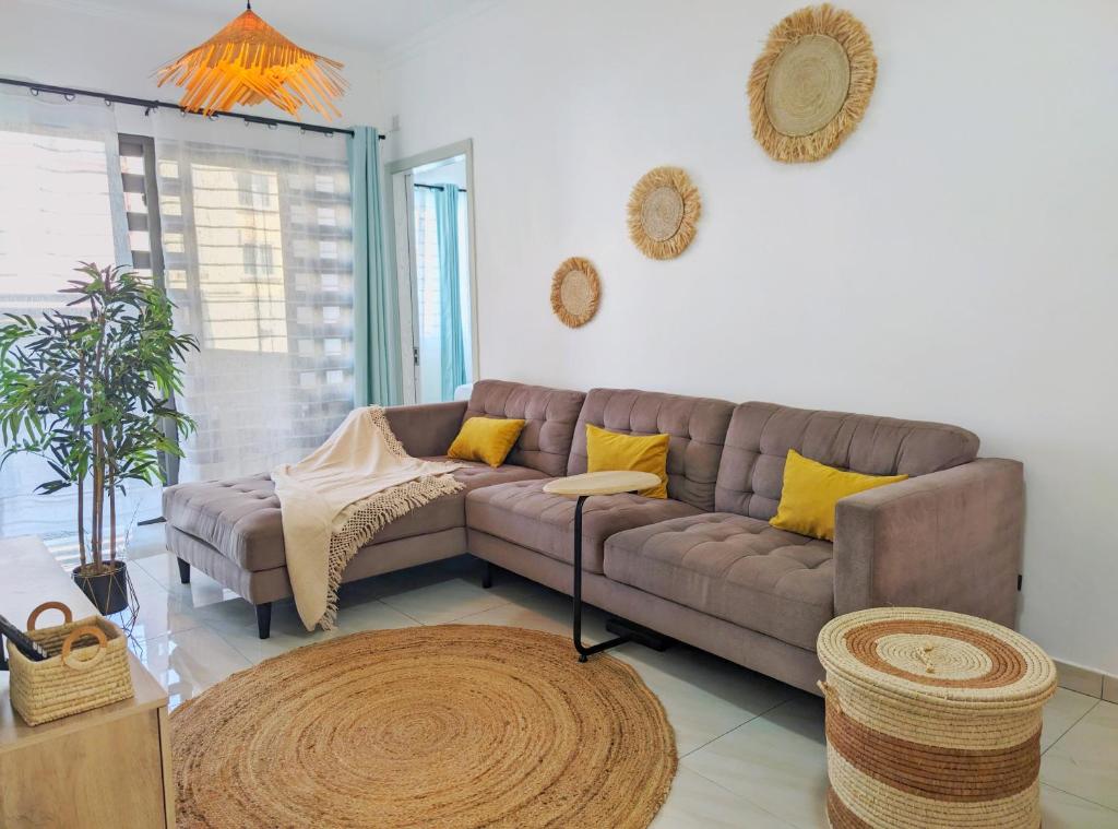 een woonkamer met een bruine bank en gele kussens bij Mon petit paradis in Flic-en-Flac