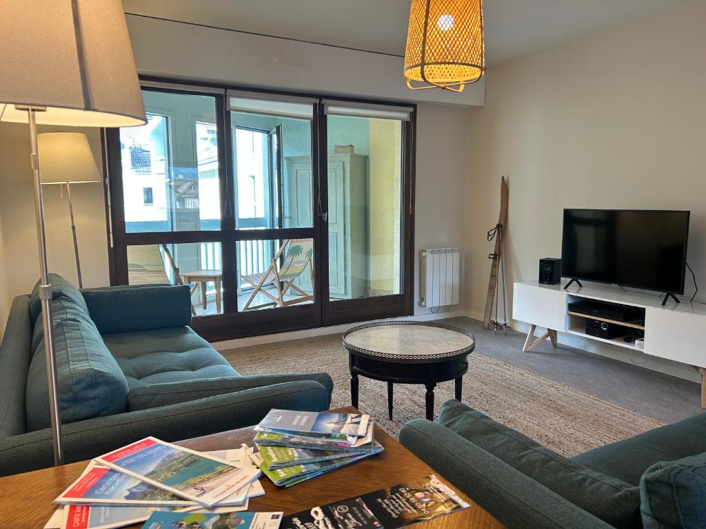 een woonkamer met een bank en een tv bij Appartement 109 in Sallanches