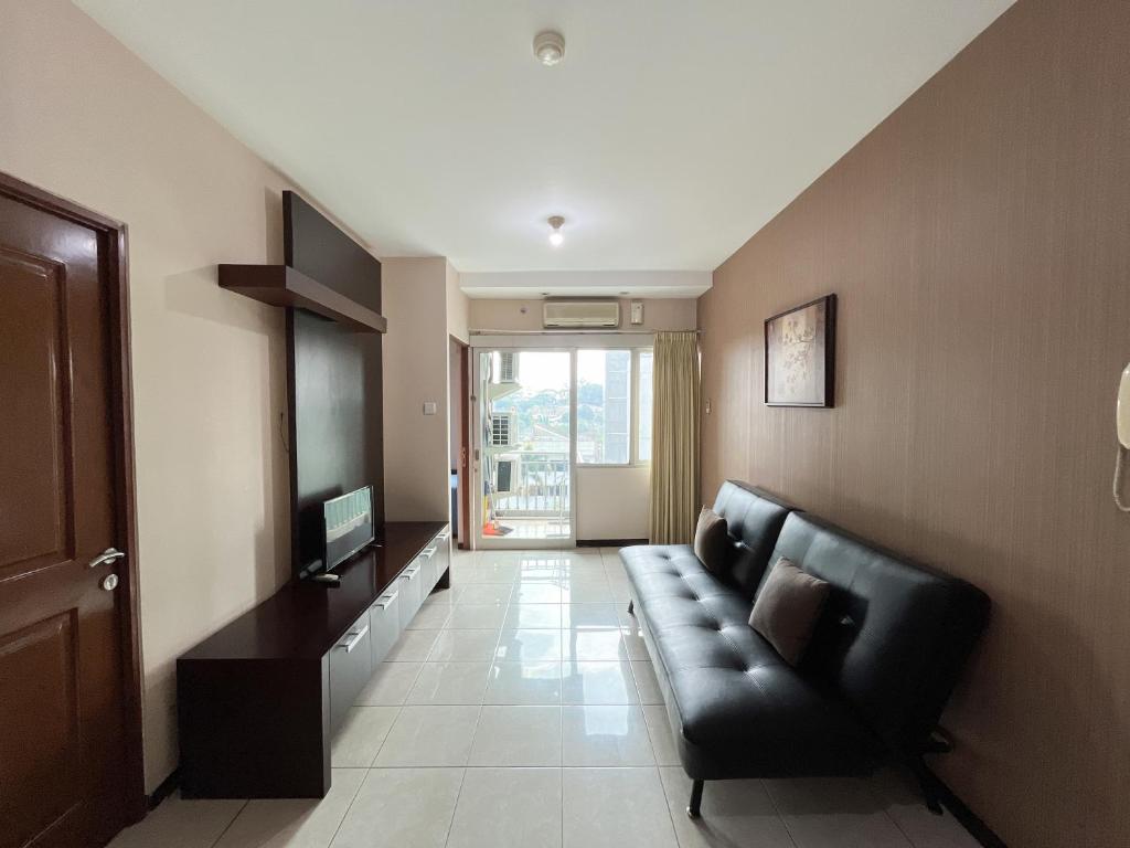 a living room with a black couch and a television at Galeri Ciumbuleuit Apartment 1 2BR 1BA - code 9A in Bandung