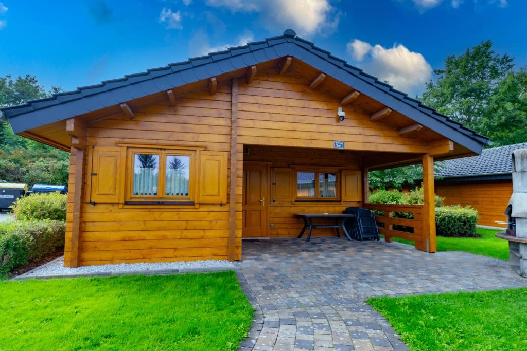 un cobertizo de madera con una mesa en un patio en Ferienpark Waldsiedlung, en Großkoschen