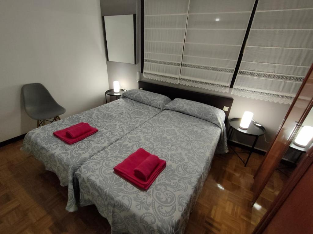 - une chambre avec un lit doté de 2 oreillers rouges dans l'établissement CASA DANIELA APARTAMENTOS-The pilgrim's house apartments, à Estella