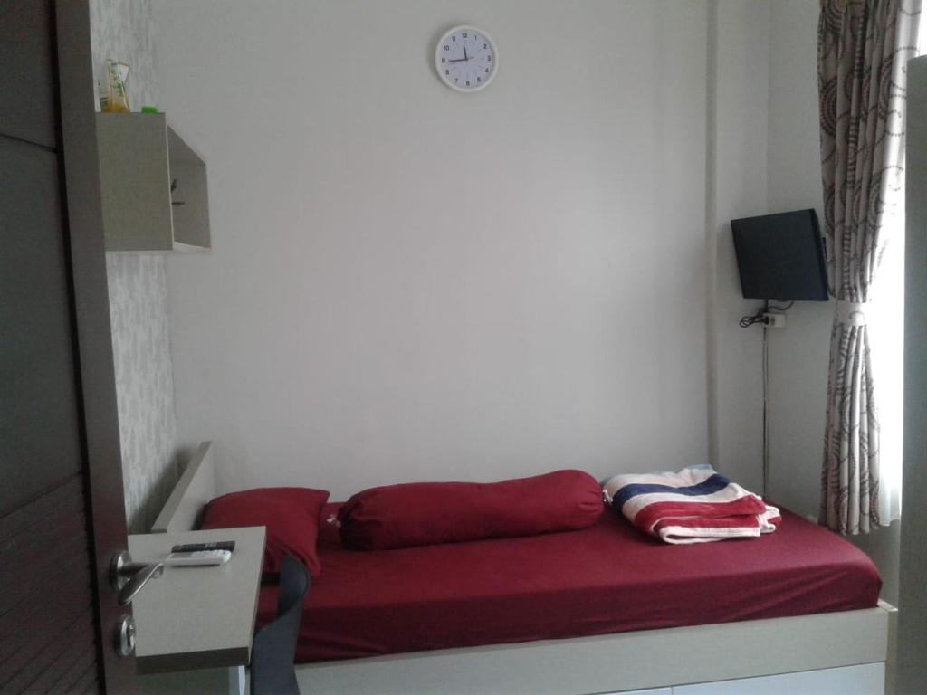 a red couch in a room with a clock on the wall at Rukost columbus in Karawang