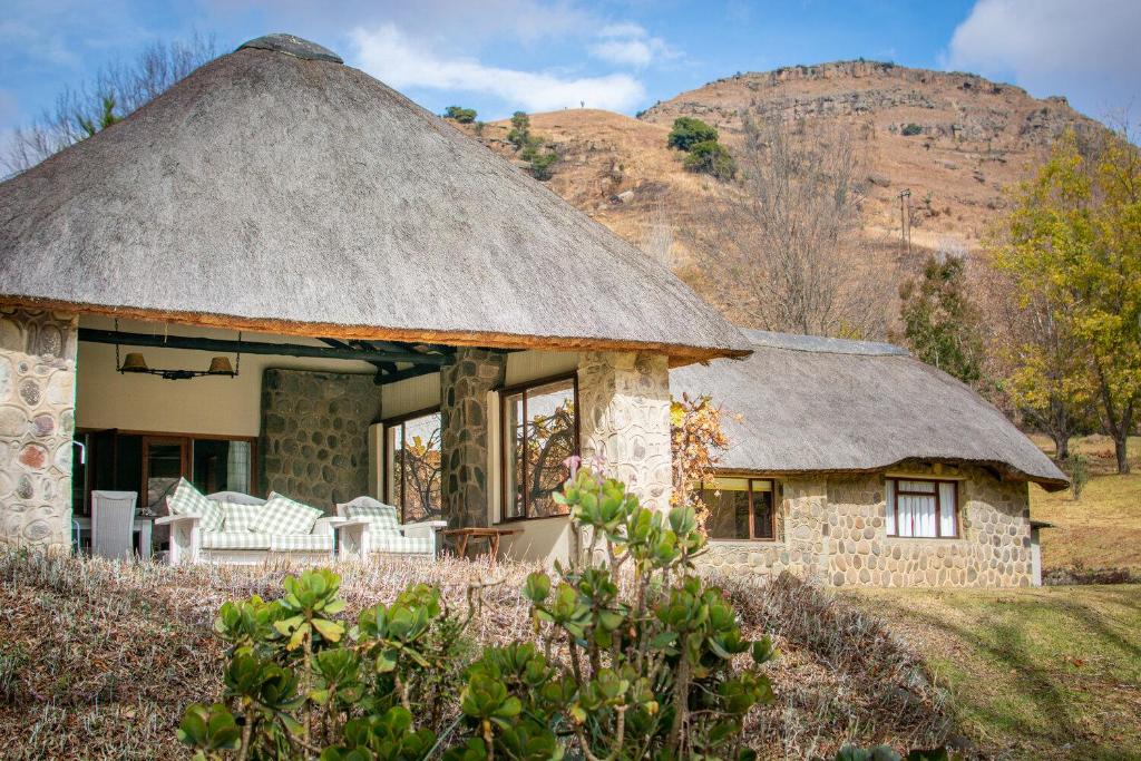 a thatch roofed house with a thatched roof at Lolambazo Country House & Cottage - Giants Castle Drakensberg in Mahlutshini