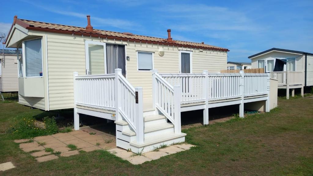 a white house with white railings and a porch at Holiday Caravan in Clacton-on-Sea