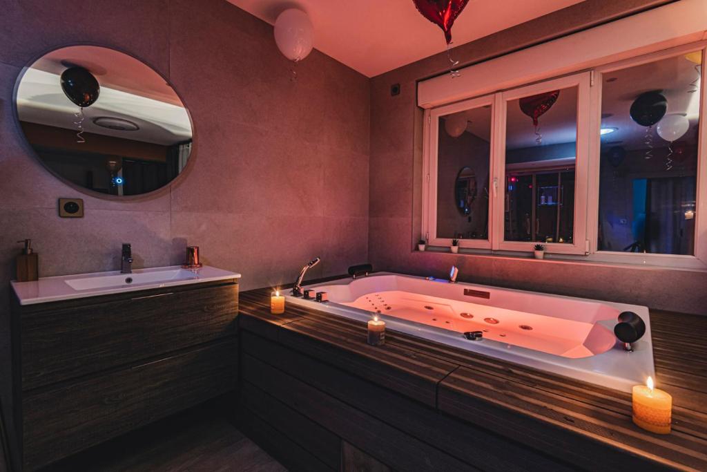La salle de bains est pourvue d'une baignoire, d'un lavabo et de miroirs. dans l'établissement MV Suite & Spa, à Reims