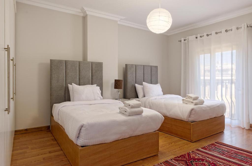 2 letti in una camera da letto con pareti bianche e pavimenti in legno di VESTA - Heliopolis Residence a Il Cairo