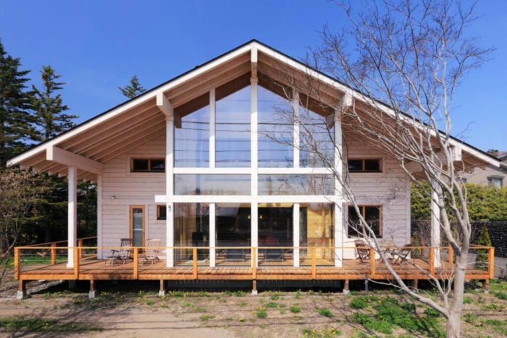 Casa grande con una gran ventana en una terraza en 浅間山を眺めるフインランドログハウス en Kutsukake