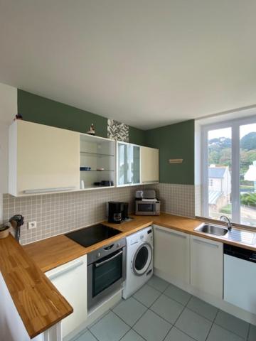 a kitchen with white cabinets and a sink and a dishwasher at Le Château de Sable in Plougasnou