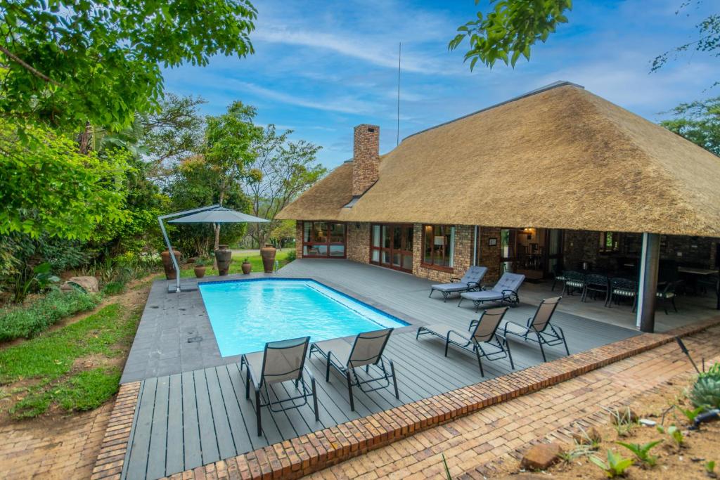 ein Haus mit einem Strohdach und einem Pool in der Unterkunft Kruger Park Lodge Unit No 441 with Private Pool in Hazyview