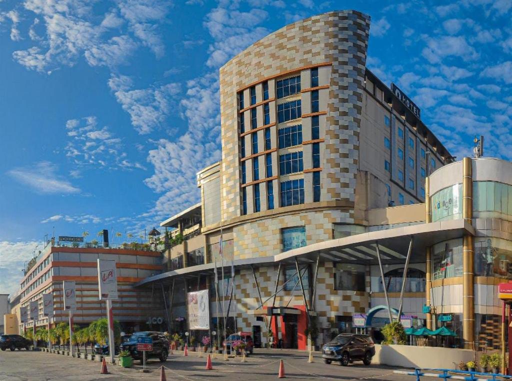 un gran edificio en una calle con coches aparcados delante en Grand Qin Hotel Banjarbaru, en Banjarbaru