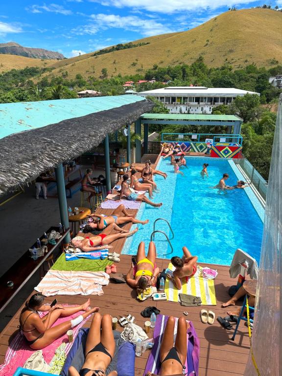 un gruppo di persone che si sdraiano sugli asciugamani in piscina di Outpost Hostel - Coron a Coron