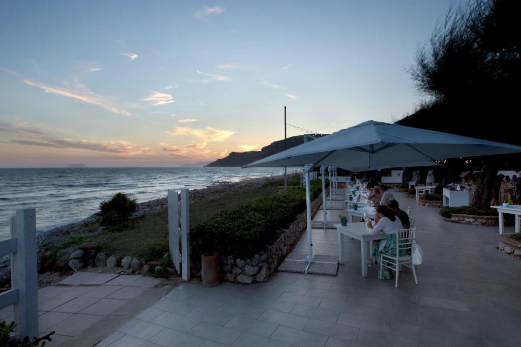 a woman sitting at a table under an umbrella on the beach at Dimora del Leone Gaeta in Gaeta