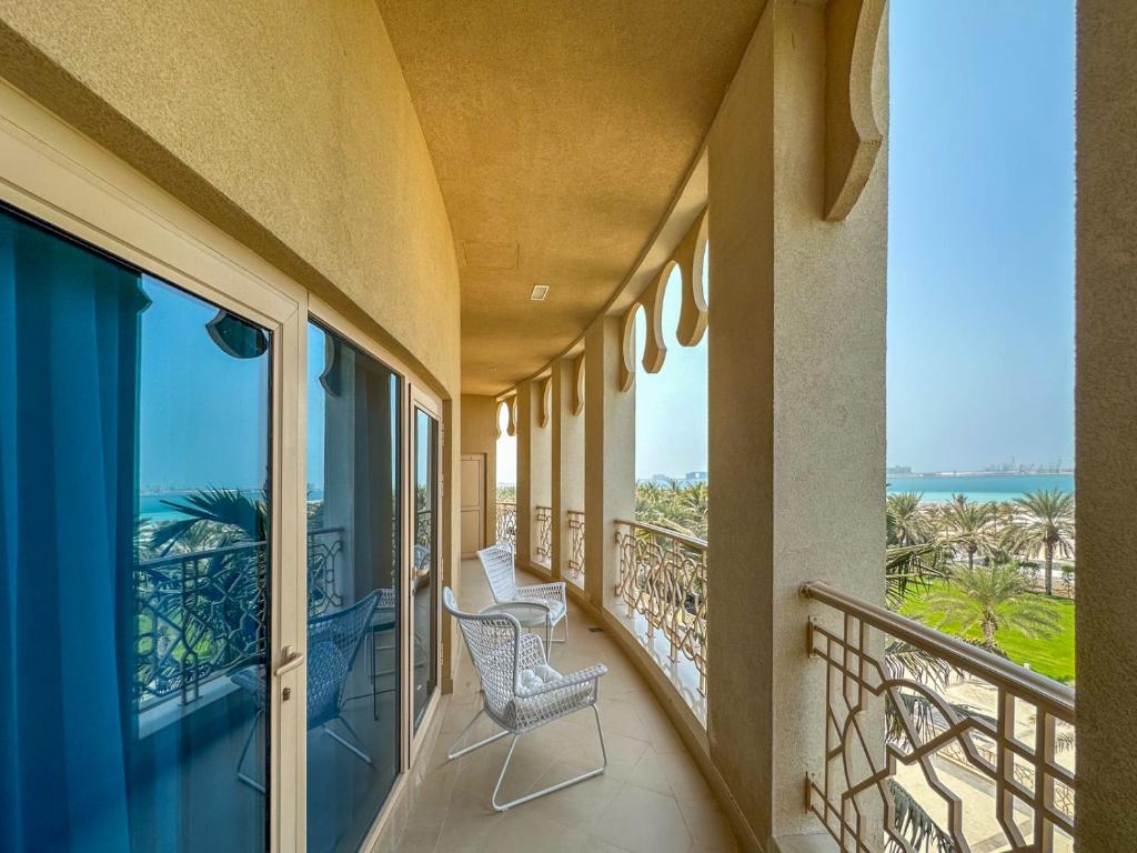 een balkon met 2 stoelen en uitzicht op de oceaan bij I Like Al Hamra Palace - Elite Beach & Golf Resort Private Suites in Ras al Khaimah