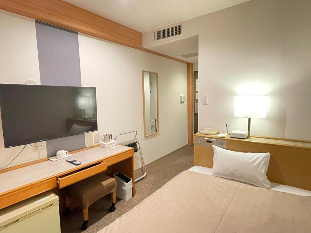 a hotel room with a desk and a tv at Sabae Daiichi Hotel in Sabae