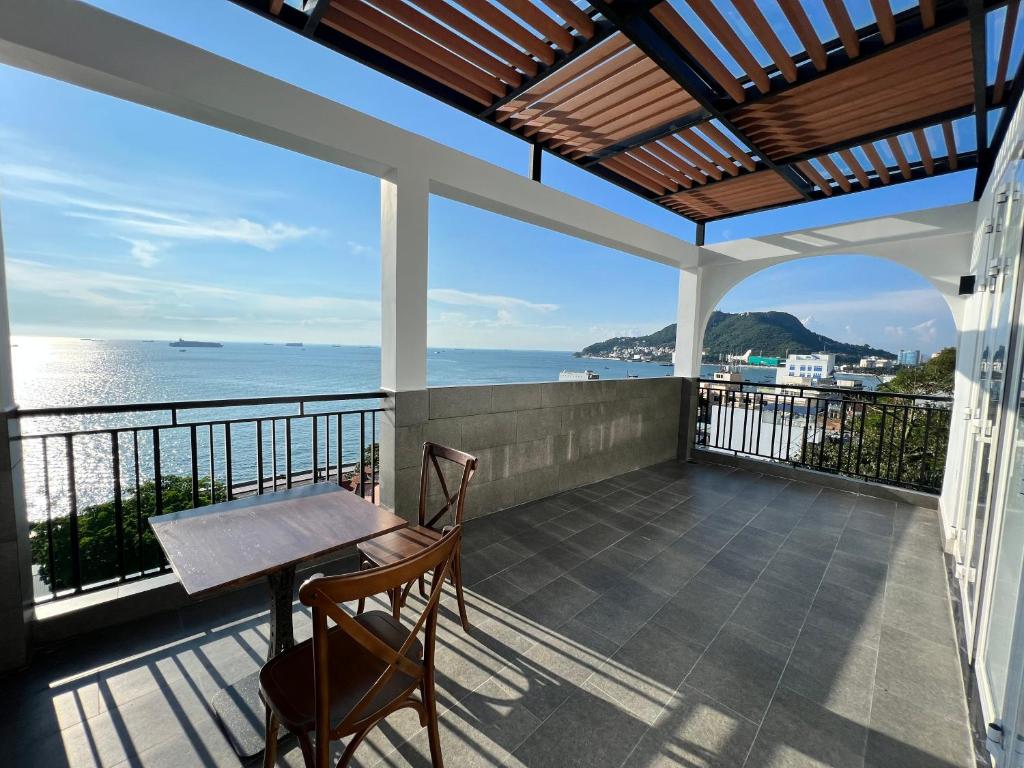 uma varanda com uma mesa e cadeiras e o oceano em KIM Apartments em Vung Tau