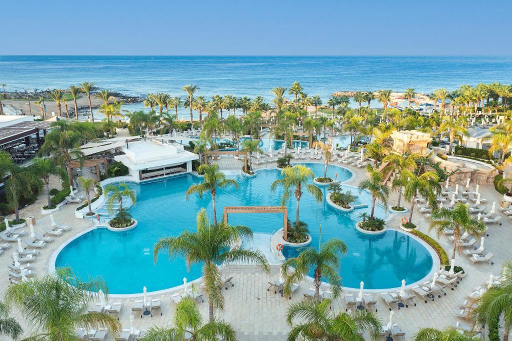 an aerial view of a resort with a pool and the ocean at Olympic Lagoon Resort Paphos in Paphos City