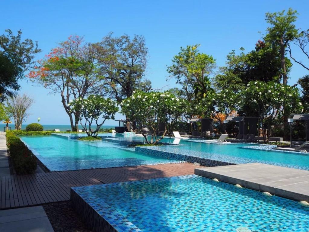 a large swimming pool with trees in the background at Baan Sandao Unit 303 in Hua Hin