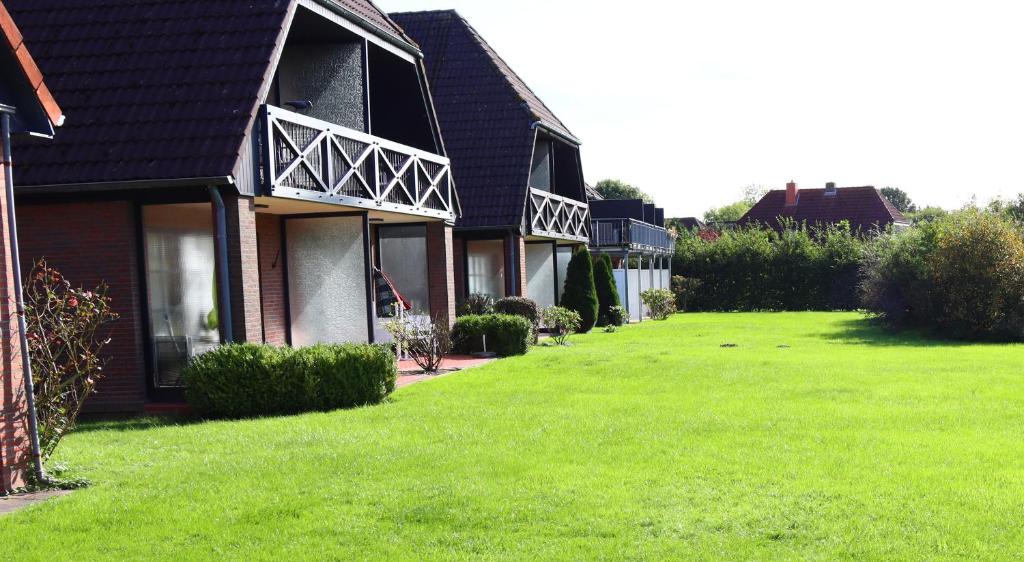 uma casa com um relvado verde em frente em Ferienwohnung Krabbenkutter em Werdum