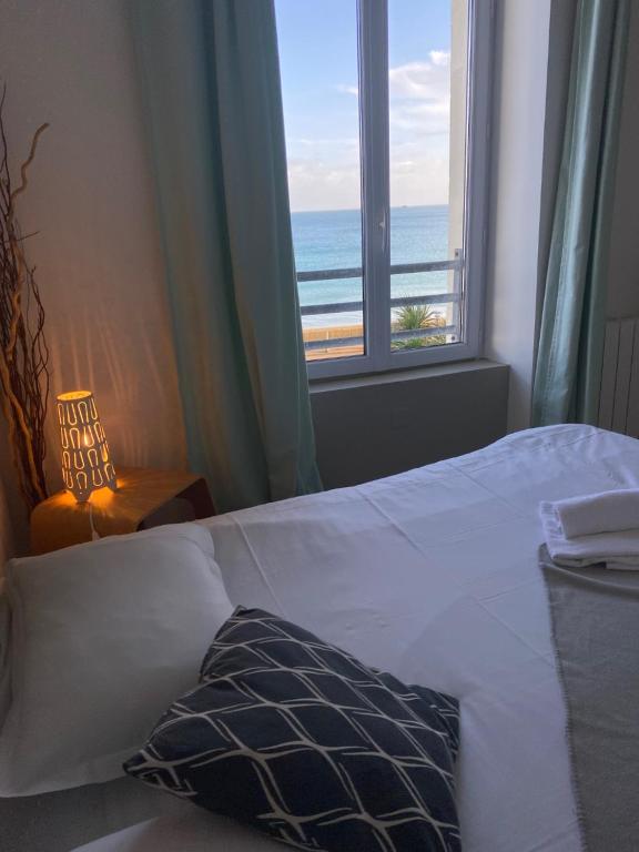 a bedroom with a bed with a view of the ocean at Le Château de Sable in Plougasnou