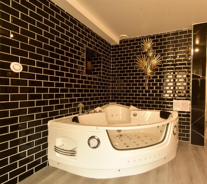 y baño con bañera y azulejos negros. en Appartement jacuzzi Gold&Night, en Verneuil d'Avre et d'Iton