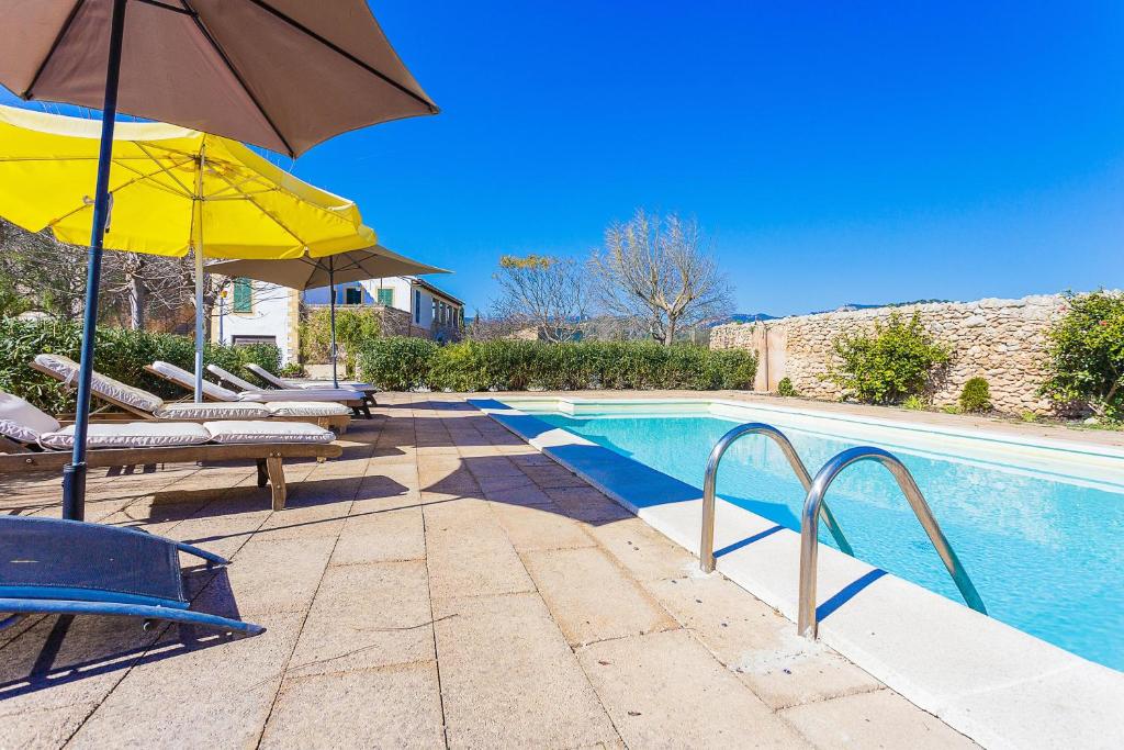 a swimming pool with umbrellas and chairs and a swimming pool at Son Corco in Consell