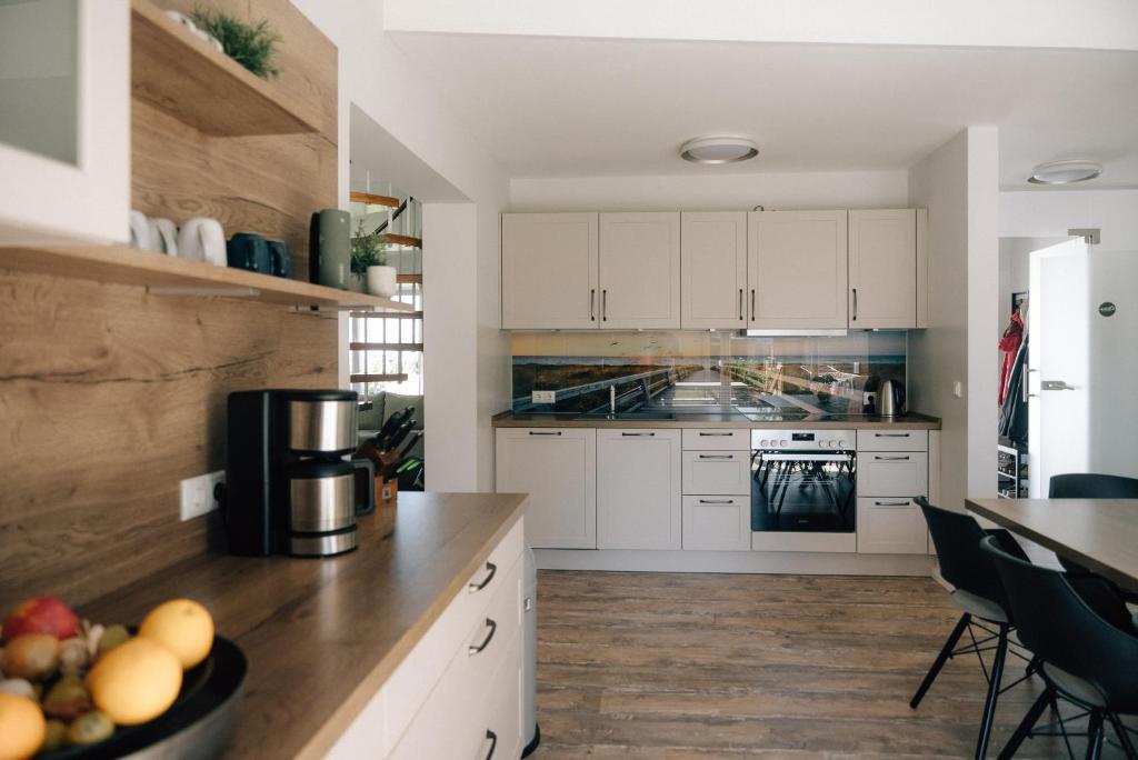 a kitchen with white cabinets and a counter with a bowl of fruit at Primesurf House Fehmarn in Fehmarn