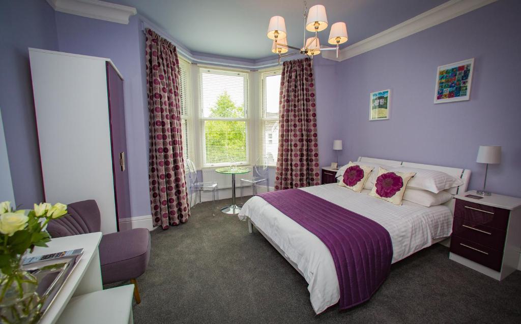 a bedroom with a bed with purple walls and a window at Studios At Glenthorne in Merthyr Tydfil