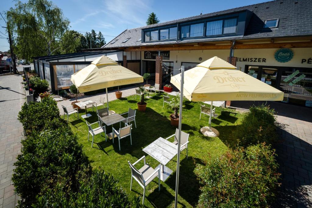 een patio met tafels en parasols bij Pipacs Panír & Grill Garden Vendégház in Győrújbarát