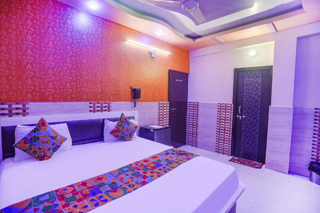 a bedroom with a large bed with colorful pillows at FabExpress Kanha Dham in Kānpur
