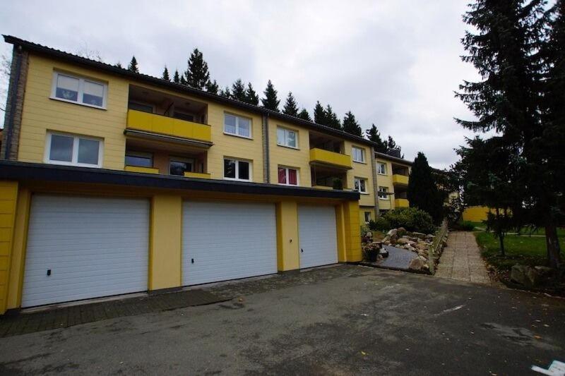 ein großes gelbes Gebäude mit zwei Garagentüren auf einem Parkplatz in der Unterkunft Ferienwohnung Mattejiet in Sankt Andreasberg