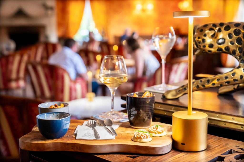 a wooden table with a glass of wine and food at Le Manoir De La Poterie & Spa in Cricquebœuf