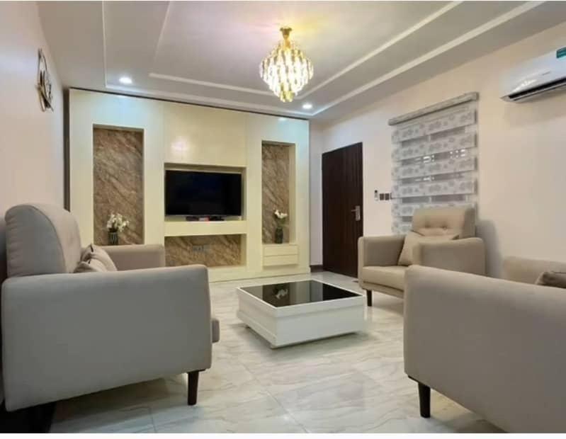 uma sala de estar com dois sofás e uma televisão em Asher’s Villa em Garki