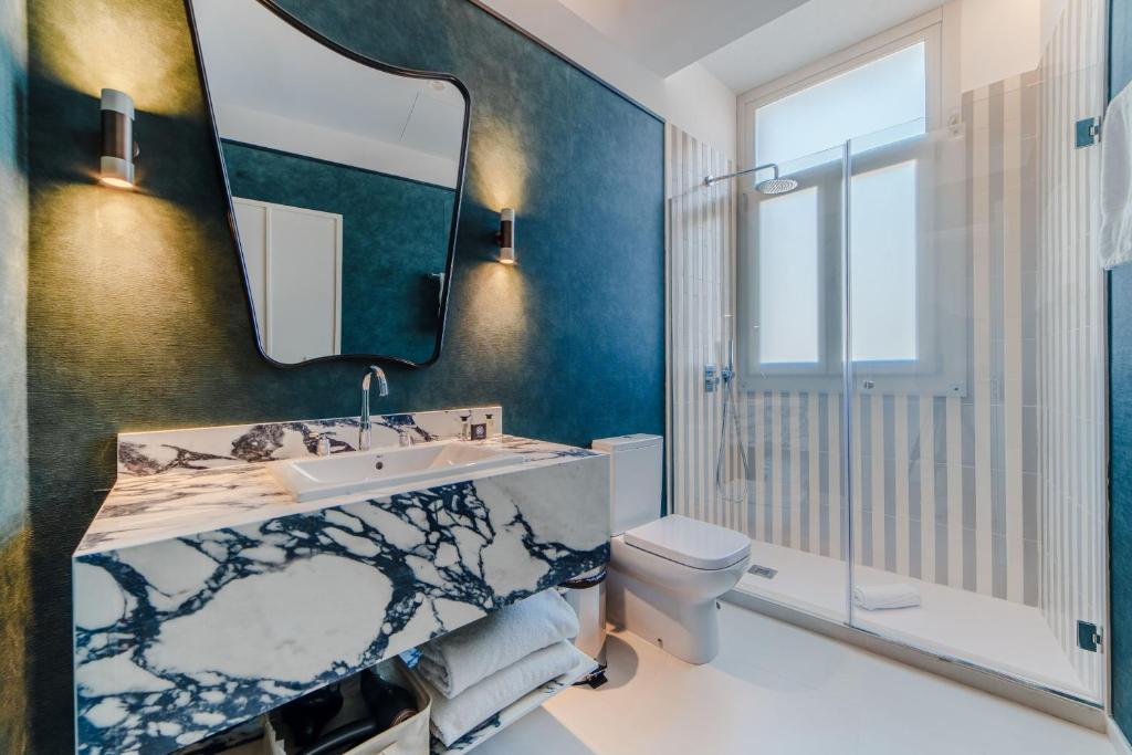 een badkamer met een wastafel, een toilet en een spiegel bij Apartamentos Soho Boutique Hoy No Me Puedo Levantar in Madrid