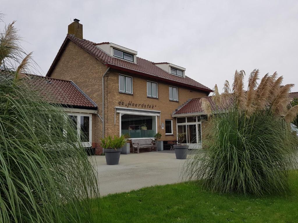 een groot bakstenen huis met een patio ervoor bij Sportpension Heartstay in Midsland