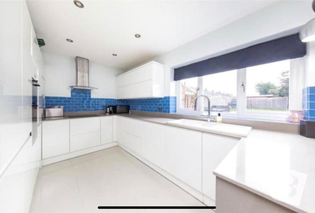 a white kitchen with a sink and a window at End of Terrace 4 bedroom 2 living room home in London in Harold Wood