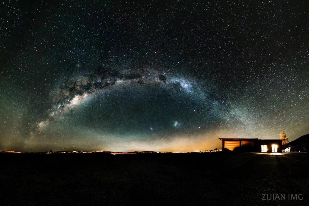 a starry night with a cabin and the milky way at GH Twizel Holiday Cottage in Twizel
