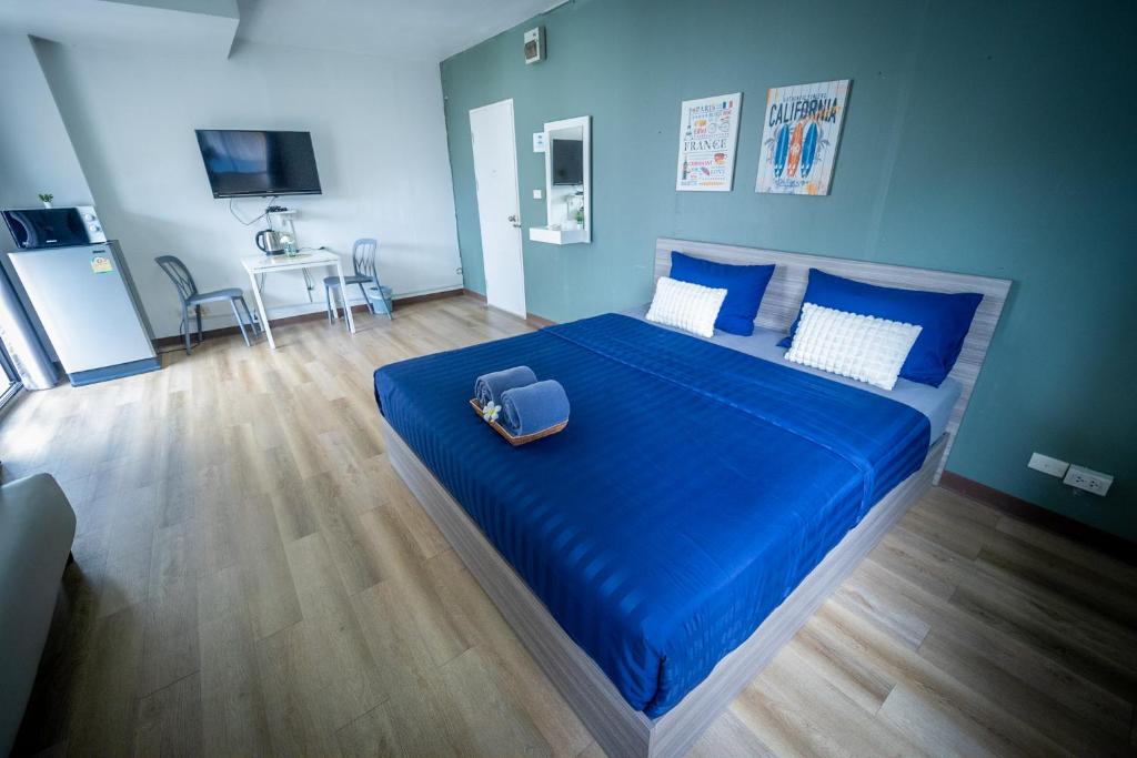 um quarto com uma cama com lençóis azuis e uma mala em Baansuay Rattanathibet Apartment em Nonthaburi