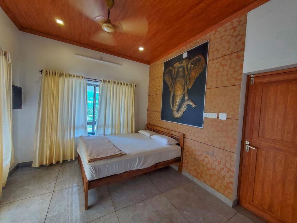 a bedroom with a bed with a picture of an elephant on the wall at zoz Vagamon in Vagamon