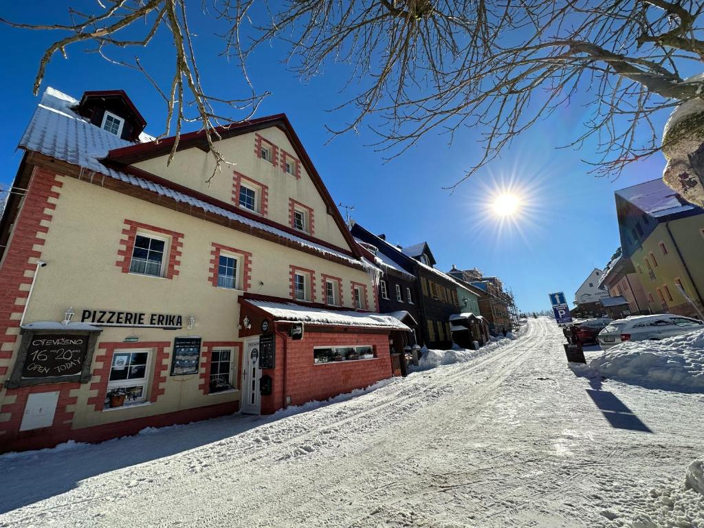 een gebouw op een besneeuwde straat met de zon in de lucht bij Penzion Erika in Boží Dar