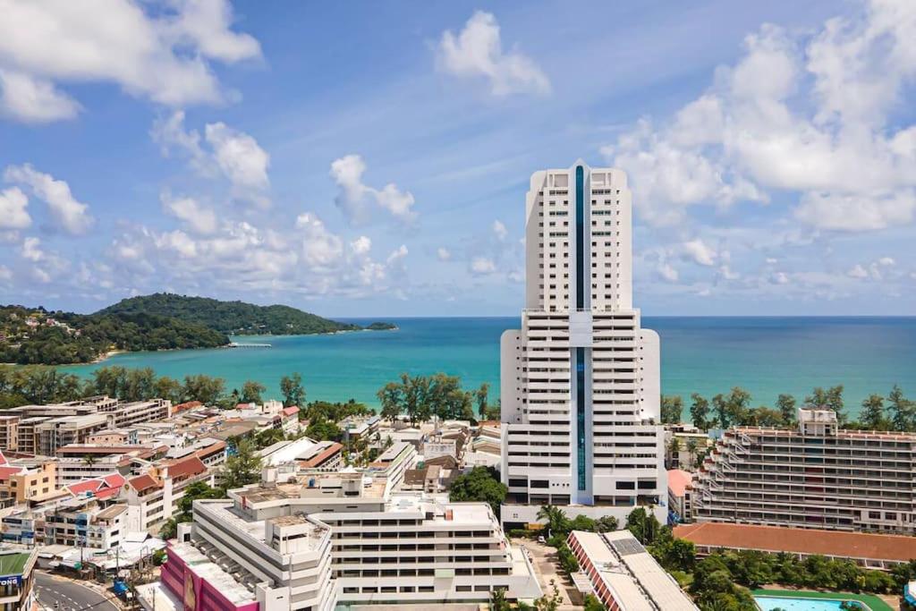 Patong Tower 2 Bedroom Apartment في شاطيء باتونغ: مبنى أبيض طويل أمام المحيط