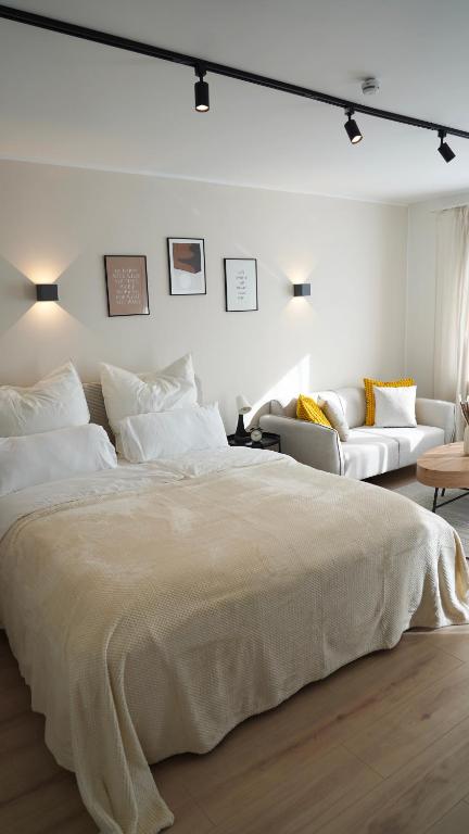 a white bedroom with a large bed and a couch at Zentral & Modern Nähe Düsseldorf und Köln in Wuppertal
