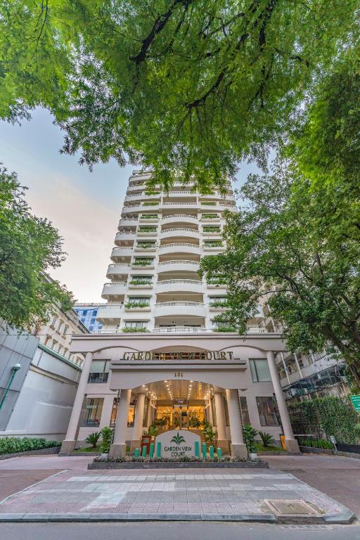 un edificio blanco alto con una tienda delante en Garden View Court Suites Ho Chi Minh City, en Ho Chi Minh