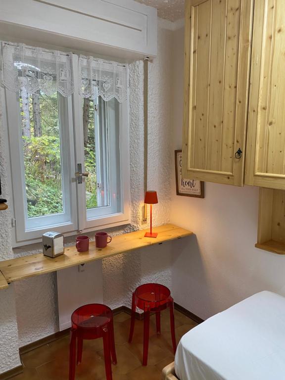 een slaapkamer met 2 rode stoelen en een bureau met 2 ramen bij Suite Neve in Madesimo
