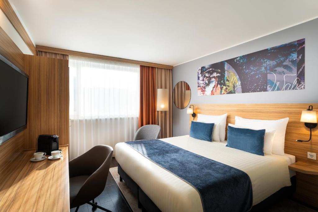 ウィーンにあるLeonardo Hotel Vienna Schönbrunnのベッドとテレビが備わるホテルルームです。
