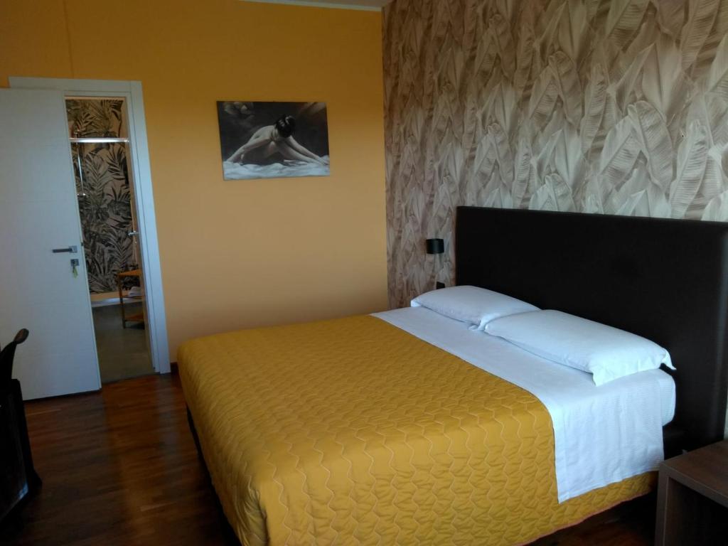 a bedroom with a large bed with a yellow bedspread at House Volusia in La Giustiniana