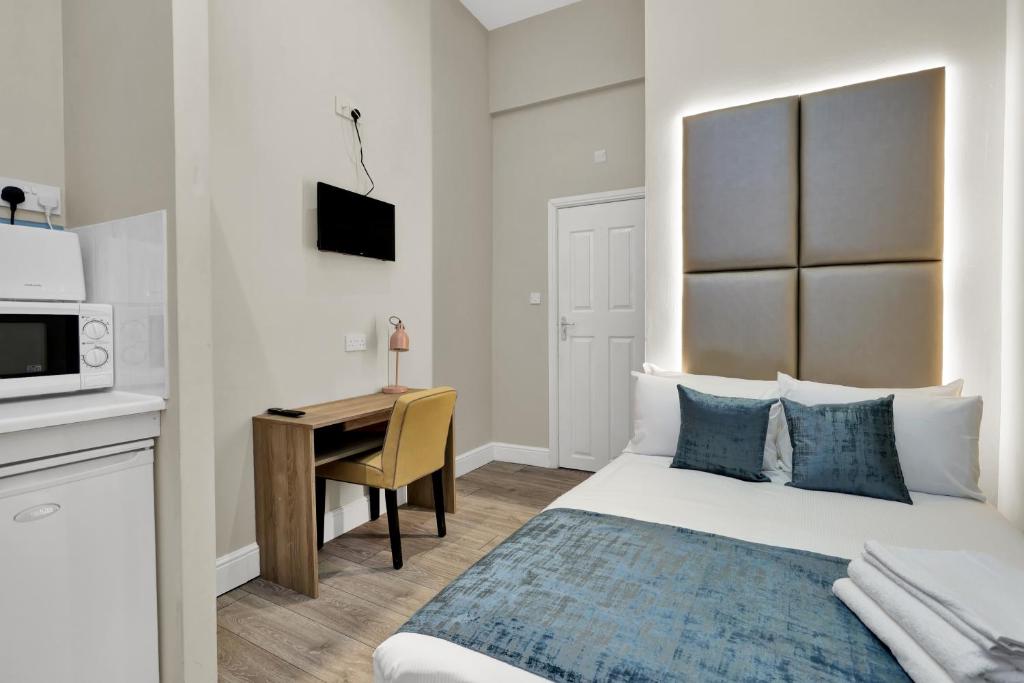 um quarto com uma cama, uma secretária e um micro-ondas em Chic Stay in London em Londres