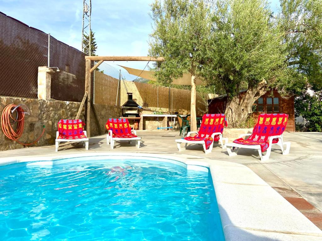 una piscina con 2 sillas y un grupo en Casa Los Kikos By Solymar Holiday, en Alcaucín