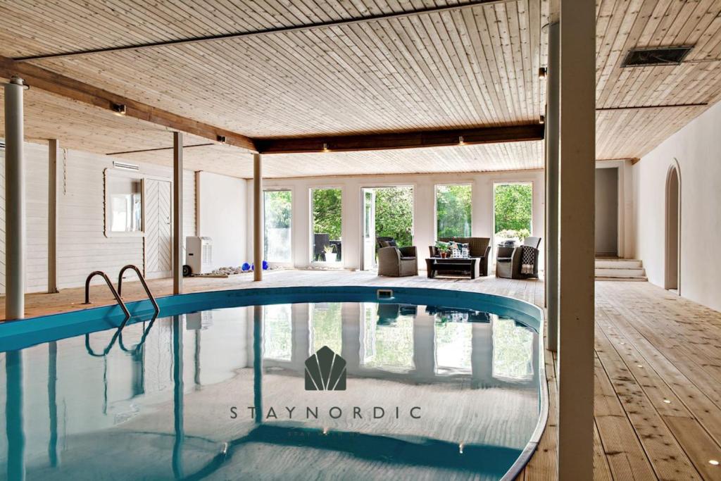 a swimming pool in a house with a wooden ceiling at Large and beautifully decorated pool house in Tomelilla, Österlen in Tomelilla