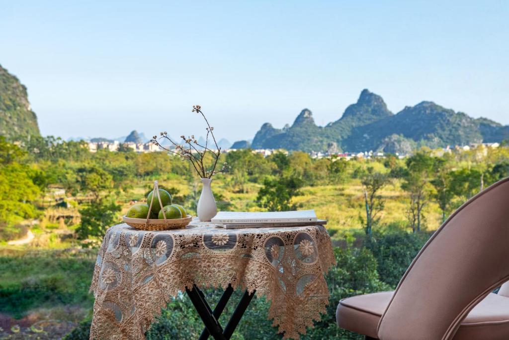 einen Tisch mit einer Vase und einer Schale Obst darauf in der Unterkunft Guilin Village Creek Inn in Guilin