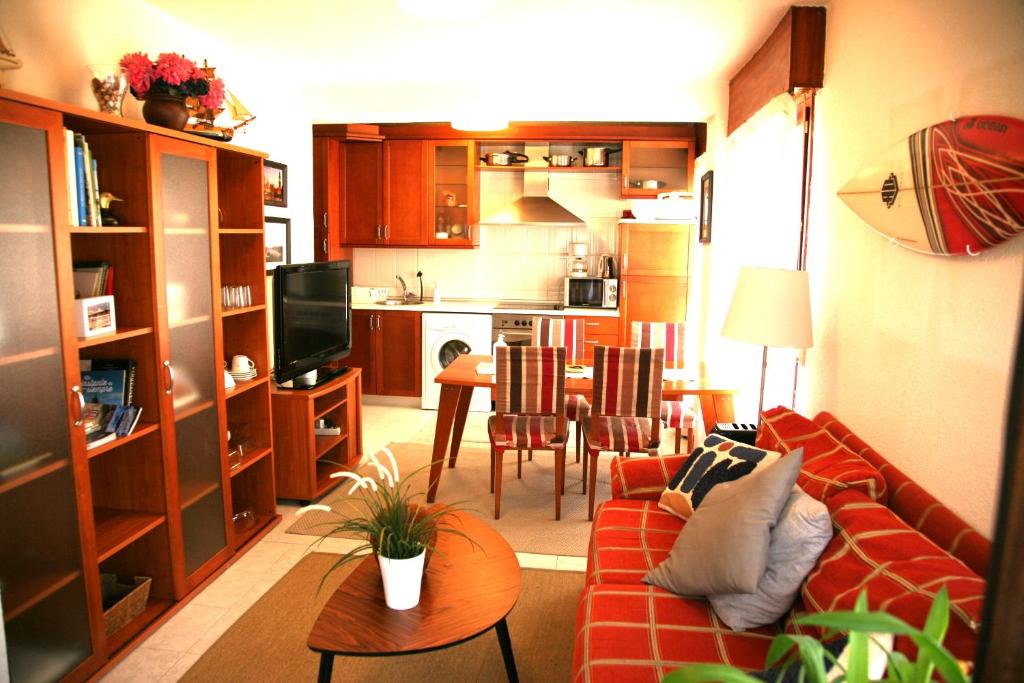 sala de estar con sofá rojo y cocina en Apartamento Somo completo 200m de la playa para 5 personas maximo, en Somo